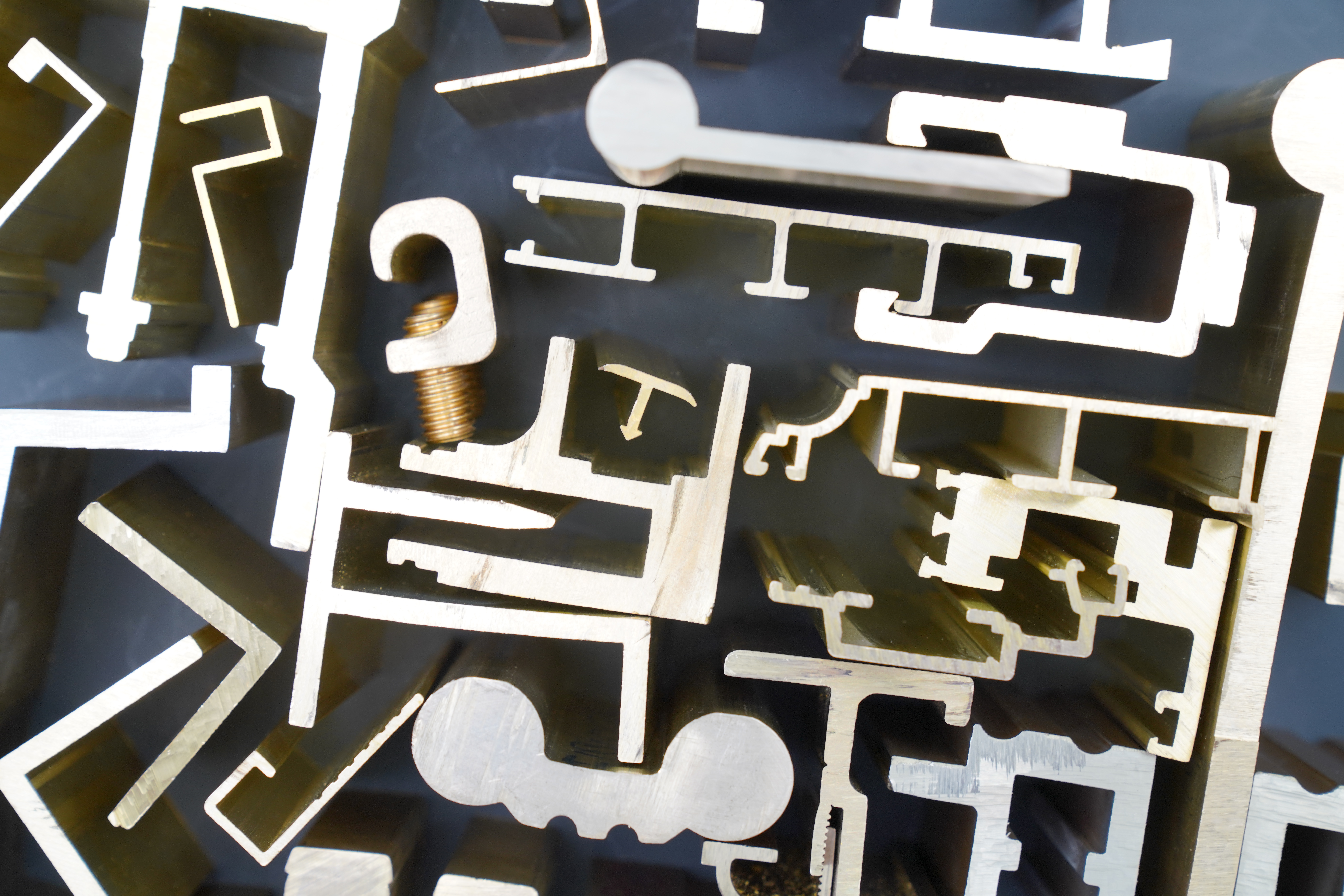 Assorted cut brass profile extrusion ends in channel, angle, hook and T-section shapes