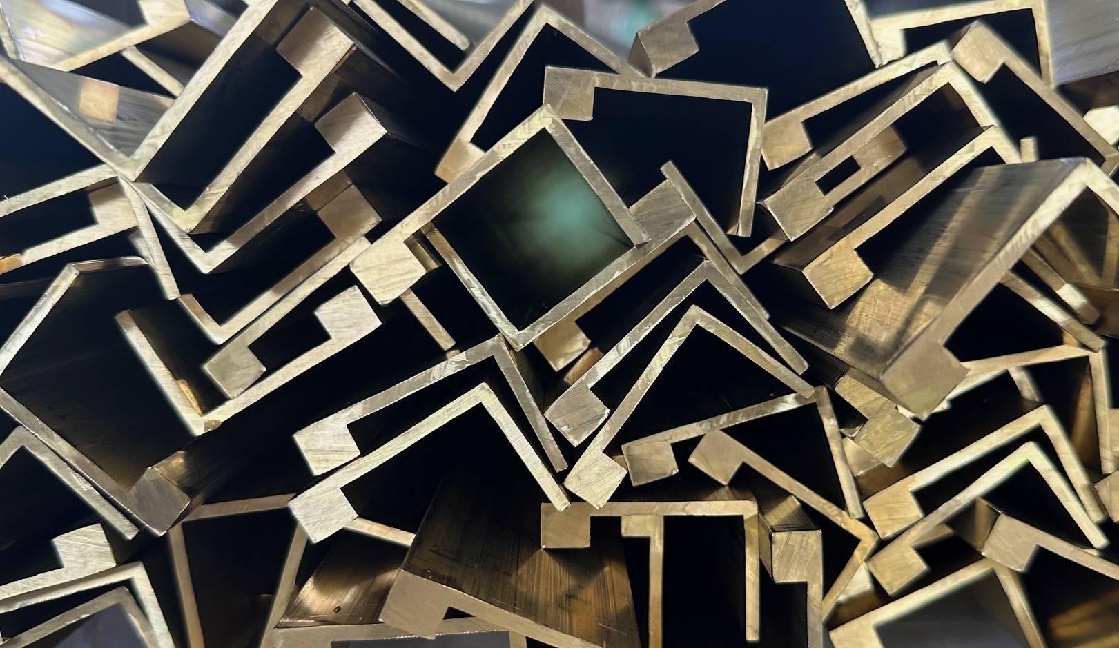 Close-up pile of cut brass profile ends in angle, channel and stepped sections